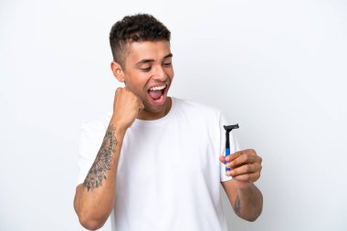 Young Brazilian man shaving his beard isolated on white background celebrating a victory