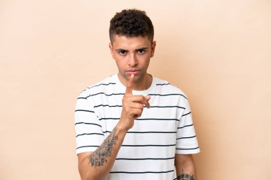 Young Brazilian man isolated on beige background frustrated and pointing to the front