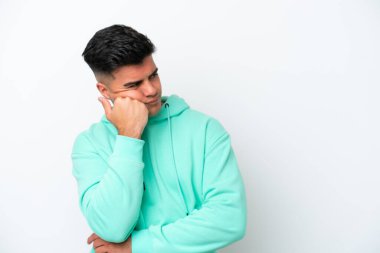 Beyaz arka planda soyutlanmış, yorgun ve sıkılmış bir ifadeyle genç, beyaz, yakışıklı bir adam.