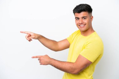 Beyaz arka planda izole edilmiş beyaz tenli yakışıklı bir adam, parmağını yana uzattı ve bir ürün sundu.