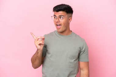 Pembe arka planda soyutlanmış beyaz, yakışıklı bir adam çözümü bulmak için parmağını kaldırıyor.