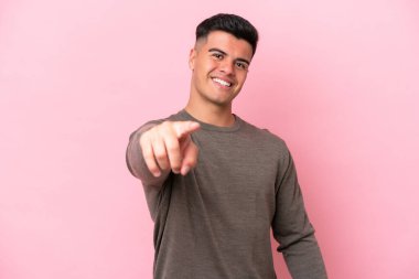 Pembe arka planda izole edilmiş beyaz, yakışıklı bir adam mutlu bir ifadeyle öne bakıyor.