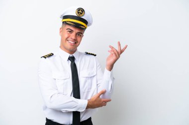 Uçak pilotu, beyaz arka planda izole edilmiş beyaz tenli bir adam, davet edilmek üzere ellerini yana uzatıyor.