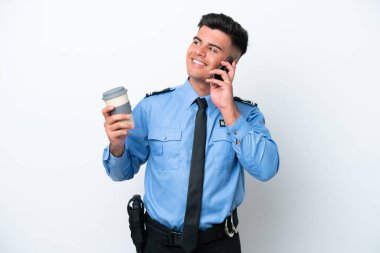 Beyaz arka planda izole edilmiş genç bir beyaz adam elinde kahve ve bir cep telefonu tutuyor.