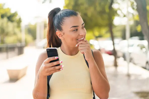 Молодая Красивая Женщина Использует Мобильный Телефон Открытом Воздухе Думая Идее — стоковое фото