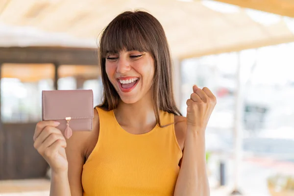 屋外で勝利を祝う財布を持っている若い女性 — ストック写真