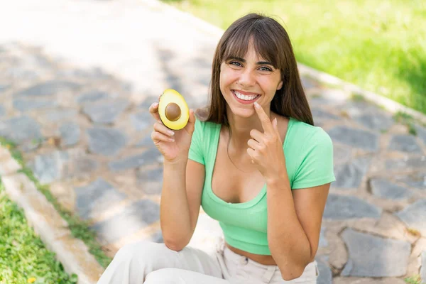 Junge Frau Freien Hält Eine Avocado Mit Glücklichem Gesichtsausdruck — Stockfoto