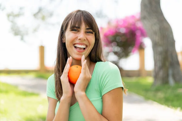 Mladá Žena Venku Drží Pomeranč Překvapeným Výrazem — Stock fotografie