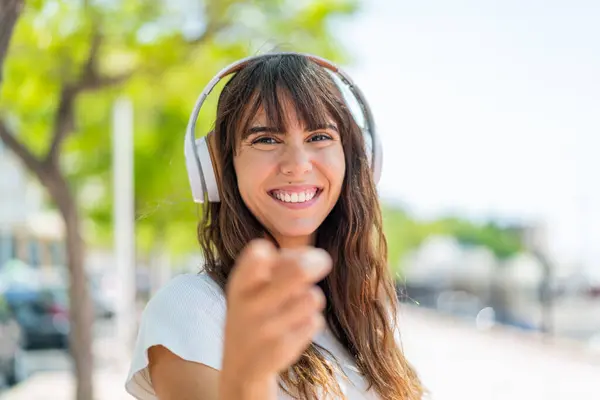 Młoda Kobieta Świeżym Powietrzu Słucha Muzyki Wskazuje Front — Zdjęcie stockowe