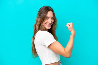 Mavi arka planda izole edilmiş beyaz bir kadın güçlü bir jest yapıyor.