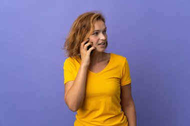 Mor arka planda izole edilmiş genç Gürcü kadın cep telefonuyla biriyle sohbet ediyor.