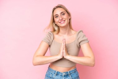 Pembe arka planda izole edilmiş genç beyaz kadın avuç içlerini bir arada tutuyor. İnsan bir şey ister.