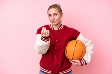 Pembe arka planda izole edilmiş genç basketbolcu kadın para hareketi yapıyor.