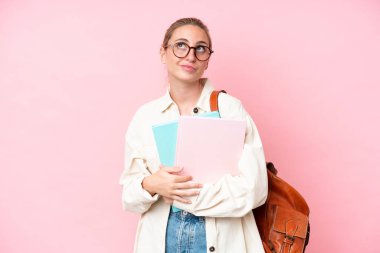 Genç beyaz kadın pembe arka planda izole edilmiş ve araştırılıyor.