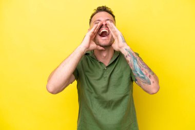 Beyaz tenli yakışıklı adam sarı arka planda izole edilmiş bağırıyor ve bir şeyler söylüyor.
