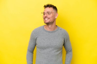 Sarı arka planda izole edilmiş beyaz, yakışıklı genç adam yana bakıyor ve gülümsüyor.