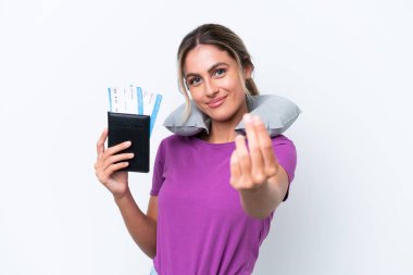 Şişirilebilir Seyahat Yastığı olan genç, güzel Uruguaylı kadın beyaz arka planda izole edilmiş para hareketi yapıyor.