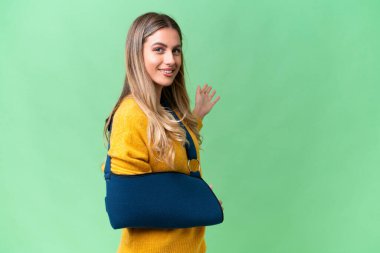 Kırık kollu genç Uruguaylı kadın ve izole edilmiş arka planda askısı var. Davet edildiği için ellerini yana uzatıyor.