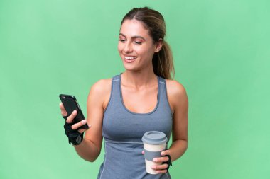 Güzel Sport Uruguaylı kadın izole edilmiş arka planda kahve ve bir cep telefonu tutuyor.