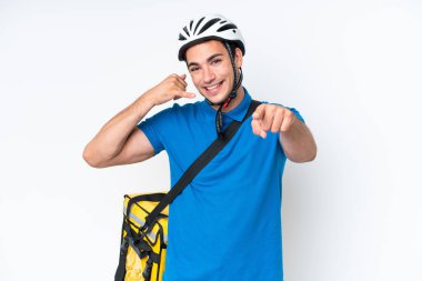 Young caucasian man with thermal backpack isolated on white background making phone gesture and pointing front