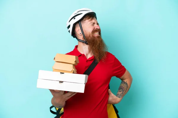 Delivery man holding pizzas and burgers isolated on blue background suffering from backache for having made an effort