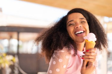 Açık havada kornet dondurması olan genç Afrikalı Amerikalı kadın.