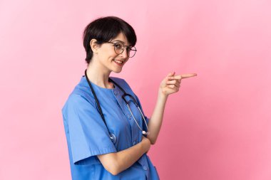 Pembe arka planda izole edilmiş bir cerrah parmağını yana doğru gösteriyor.