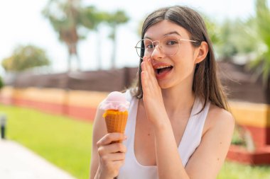 Genç ve güzel Ukraynalı bir kadın açık havada kornet dondurması ile bir şeyler fısıldıyor.