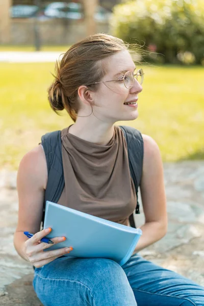 Young French girl with glasses at outdoors holding a notebook