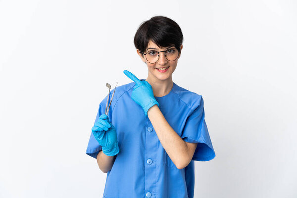 Dentist woman holding tools isolated on white background pointing to the side to present a product