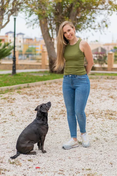 Fiatal Szőke Szabadban Imádnivaló Fekete Kutyájával — Stock Fotó