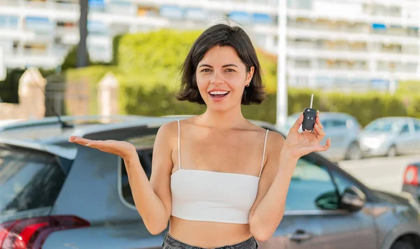若い美しいブルガリアの女性はショックを受けた表情で屋外で車のキーを保持しています — ストック写真