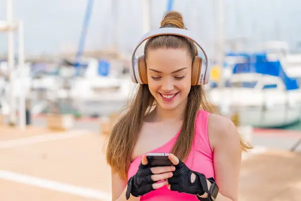 Молодая Симпатичная Спортивная Девушка Улице Слушает Музыку Смотрит Мобильный Телефон — стоковое фото