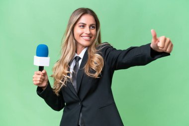 Genç, güzel Uruguaylı televizyon sunucusu izole edilmiş arka planda başparmak hareketi yapıyor.