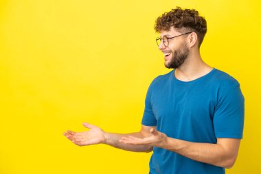 Sarı arka planda yalıtılmış yakışıklı beyaz bir adam. Sürpriz bir ifadeyle yan yana bakarken.