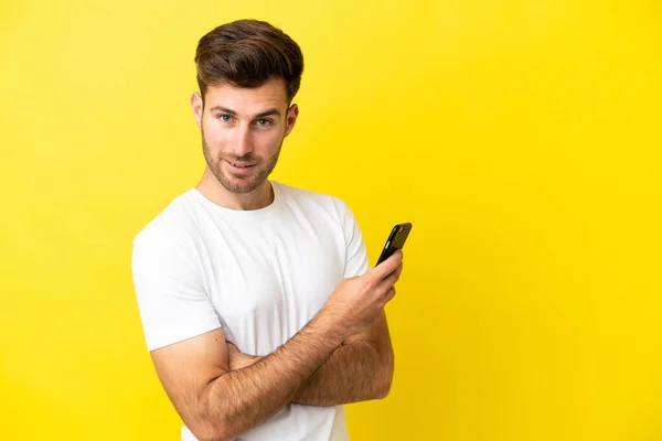Young Caucasian Handsome Man Isolated Yellow Background Holding Mobile Phone — Stock Photo, Image