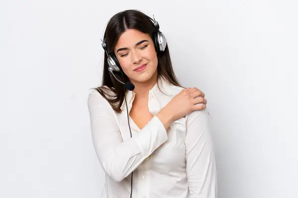 Telemarketer caucasian woman working with a headset isolated on white background suffering from pain in shoulder for having made an effort