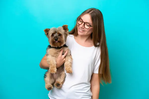 Young Lithuanian woman holding a dog isolated on blue background with happy expression