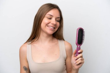 Genç Litvanyalı kadın beyaz arka planda saç tarağıyla izole edilmiş ve ona bakıyor.