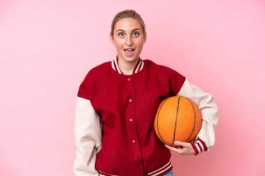Genç basketbolcu beyaz kadın. Pembe arka planda izole edilmiş. Yüz ifadesi şaşırtıcıydı.