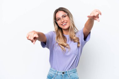 Genç Uruguaylı kadın beyaz arka planda izole edilmiş mutlu bir ifadeyle cepheyi işaret ediyor