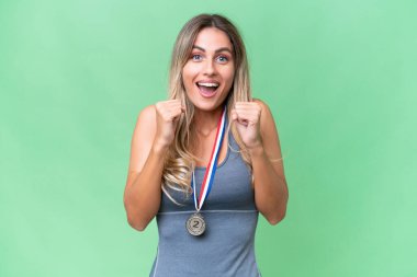 Genç ve güzel Uruguaylı sporcu, arka planda izole edilmiş madalyaları olan kadın galibiyeti kutluyor.