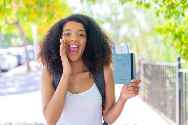 Pasaportu elinde tutan genç Afrikalı Amerikalı kadın ağzı açık bağırıyor.