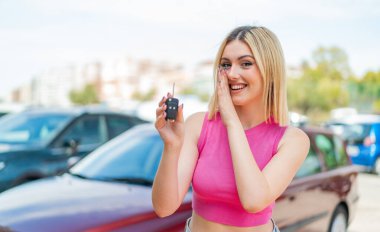 Dışarıda arabanın anahtarlarını tutan güzel sarışın kadın fısıldıyor.