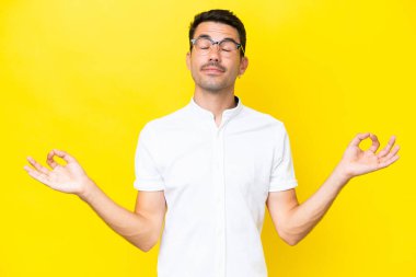 Zen pozisyonunda, izole edilmiş sarı arka planı olan yakışıklı bir genç.