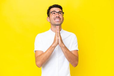 Soyutlanmış sarı arka planda genç yakışıklı bir adam avuç içlerini bir arada tutuyor. İnsan bir şey ister.