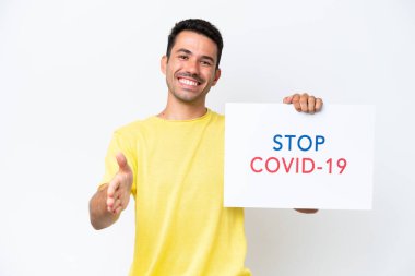 Beyaz arka plan üzerinde genç yakışıklı bir adam elinde yazılı bir levha ile Covid 19 'u durdurun bir anlaşma yapıyor