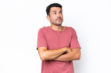 Soyutlanmış beyaz arka planda genç yakışıklı bir adam omuzlarını kaldırırken şüpheyle hareket ediyor.