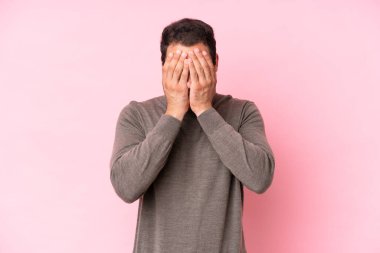 Pembe arka planda izole edilmiş, yorgun ve hasta bir ifadeyle genç beyaz bir adam.