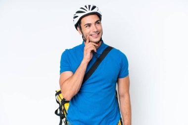 Beyaz arka planda izole edilmiş termal sırt çantalı beyaz bir adam yukarı bakarken bir fikir düşünüyor.